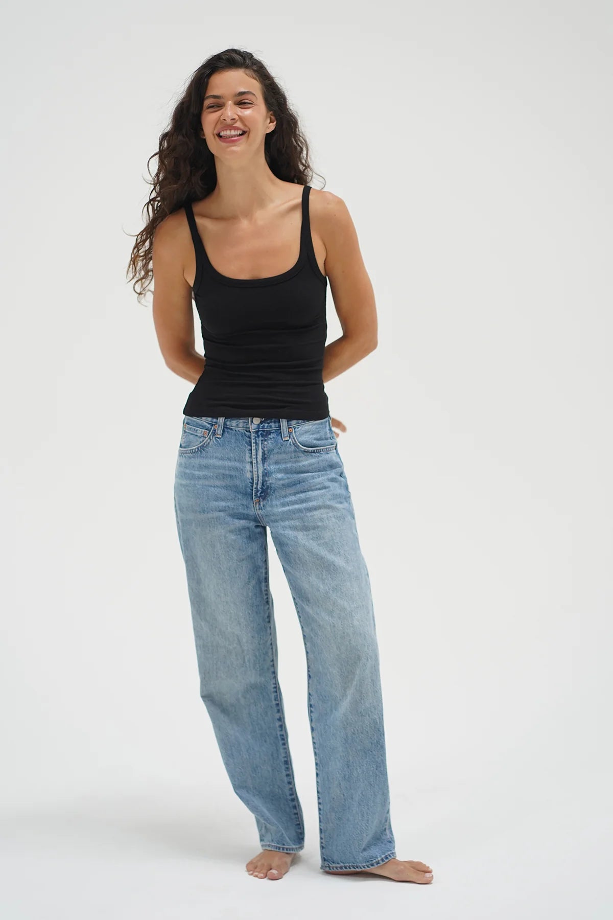 Woman wearing a black tank top and light blue jeans on a white background. LNA Timeless Ribbed Tank at Coco Kimono