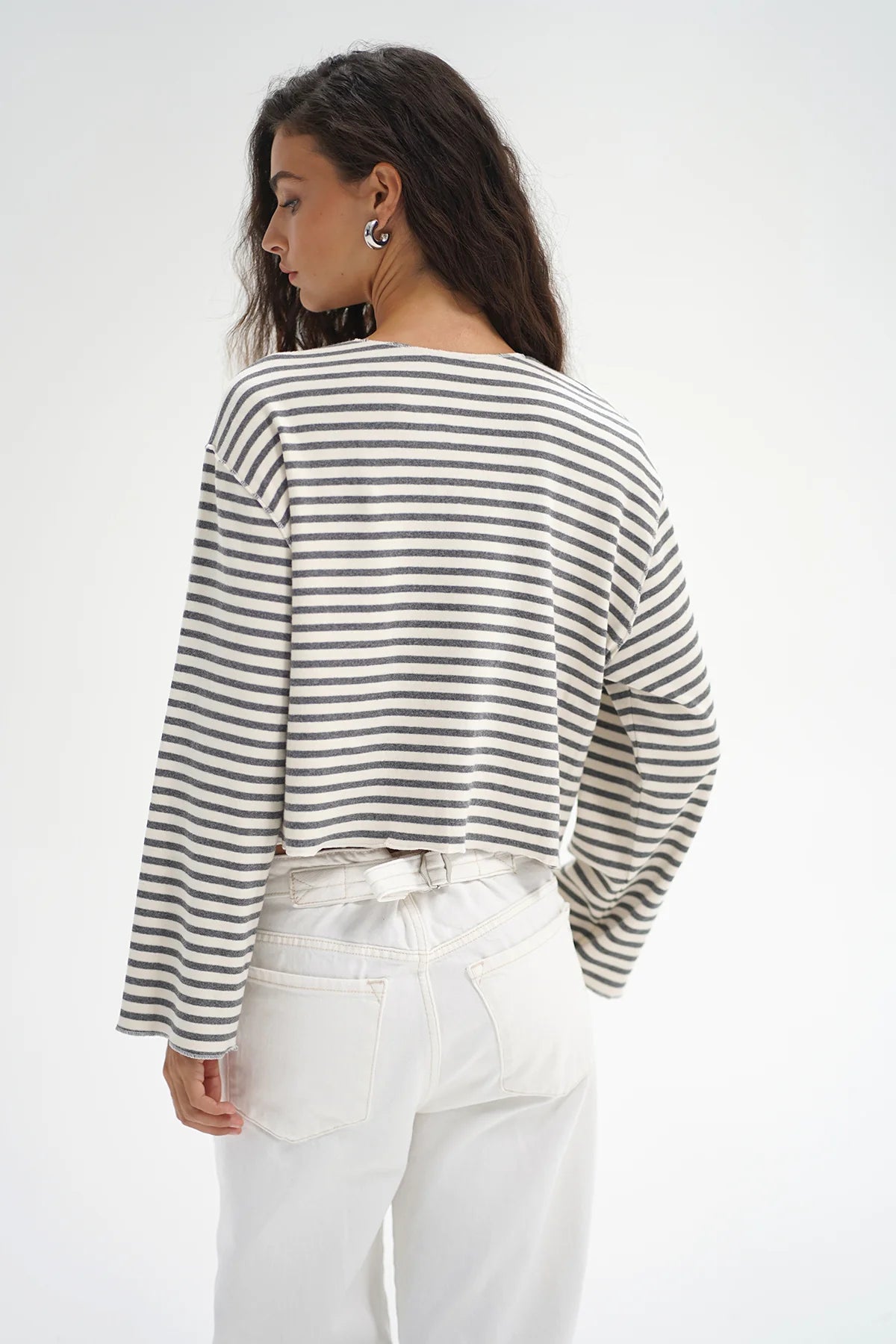 Woman wearing a striped long-sleeve top and white pants on a plain background. LNA Kincaid Cardigan Greyscale Stripe at Coco Kimono Boutique
