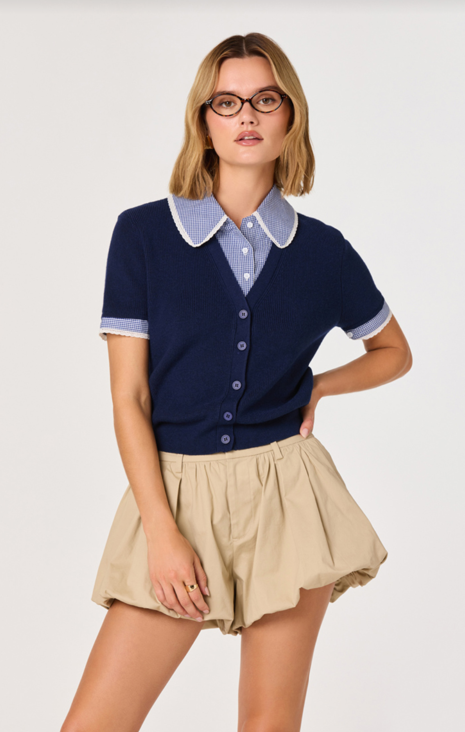 ASTR The Label Marlee Navy Plaid Mixed Media Cardigan Sweater Coco Kimono. Woman wearing a navy cardigan, light blue shirt, and beige shorts on a white background